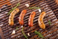 Top view of four grilling sausages on barbecue grill with some species. BBQ in the garden. Bavarian sausages Royalty Free Stock Photo