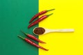 Top view, four red chili peppers with a wooden spoon on a yellow-green background Royalty Free Stock Photo