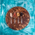 Top view of four spoons with cereal, dry fruits, and granola on a wooden board