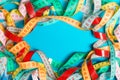 Top view of frame made of heap of colorful measure tapes on turquoise background. Keeping fit concept with empty space for your
