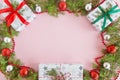 Top view on a frame from red, green and silver Christmas decorations, gift boxes and fir branches on a pink background. Royalty Free Stock Photo