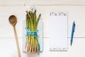 Top view of fresh asparagus on a wooden table with recipe notebook and ballpoint Royalty Free Stock Photo