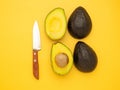 Top view of fresh avocado half and knife on a yellow background. Royalty Free Stock Photo