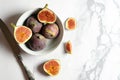 Top view fresh exotic cutted on half fig in white bowl on marble table. Food photo background. Creative scheme of the whole and Royalty Free Stock Photo