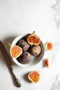 Top view fresh exotic cutted on half fig in white bowl on marble table. Food photo background. Creative scheme of the whole and Royalty Free Stock Photo