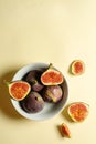 Top view fresh exotic cutted on half fig in white bowl on yellow background. Food photo background. Creative scheme of the whole Royalty Free Stock Photo