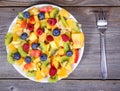 Top view of a fresh fruit salad with bananas kiwi orange blueberries and peach on plate with fork on wooden table Royalty Free Stock Photo