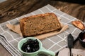 Top view fresh homemade banana bread and sliced bread on cutting board with jam strawberry and blueberry on wooden background.Heal