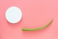 Top view of a fresh leaf of aloe vera and a white jar of cream on a pink background. Organic cosmetics with natural ingredients Royalty Free Stock Photo