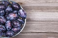 Closeup of plums in a bowl on wooden background. Top view. Royalty Free Stock Photo