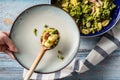 Top view on fresh prepared broccoli with gnocchi in casserole dish on the wooden table - hand of unknown person putting homemade