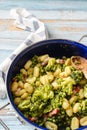Top view on fresh prepared broccoli with gnocchi in casserole dish on the wooden table - homemade healthy food in bright light