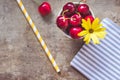 Top view of cherries on a stripped cloth and a yellow stripped straw and flower on wooden background Royalty Free Stock Photo