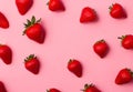 Top view of a fresh red strawberry against a pink background. Berries dispersed in a minimalistic pattern.