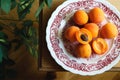 Top view of fresh ripe apricots on plate on wooden table, village atmosphere, rustic, copy space. Cosy interior. Harvest concept.