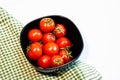 Top view of fresh ripe cherry tomatoes in small black bowl on a rustic white wooden table. Ingredients and food concept Royalty Free Stock Photo