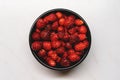 Top view of fresh ripe dark red wild strawberries in a black bowl on a white background Royalty Free Stock Photo