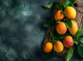 Top view of fresh, ripe mangoes with green leaves on a wooden board, dark textured background. Royalty Free Stock Photo