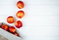 top view of fresh ripe nectarines scattered from a sack on white background with copy space