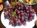 Top view of fresh ripe red grape in white plate on wooden table Royalty Free Stock Photo