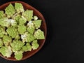 top view of fresh romanesco florets in wooden bowl on black slate plate with copy space