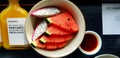 Top view of Fresh sliced of watermelon and dragon fruit in plate with bottle of orange juice on black wooden table. Royalty Free Stock Photo