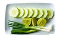 Top view of fresh spring onion, sliced cucumber and lime or lemon in white plate isolated on white background with clipping path Royalty Free Stock Photo