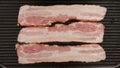 TOP VIEW: Fresh strips af bacon on a black pan