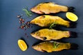 Top view of fresh tench fish with aromatic herbs, spices and vegetables on slate background, Royalty Free Stock Photo