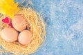 Top view of fresh chicken eggs in straw nest, red heart and daffodil on blue textured background. Happy Easter greeting Royalty Free Stock Photo