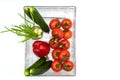 Top view of fresh vegetables that lie in a clean container: red tomatoes on a branch, red bell peppers, large cucumbers, green oni Royalty Free Stock Photo