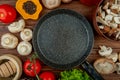 top view of fresh white mushrooms with tomatoes wooden mortar with dried herbs black peppercorns arranged around a frying pan on Royalty Free Stock Photo