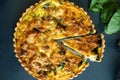 Top view freshly bake leek bacon spinach quiche on dark background