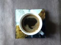 Top view of a freshly brewed black coffee in a whit mug on a square coaster