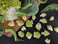 Top view of freshly cut raw romanesco broccoli florets on black slate plate, preparation of roman cauliflower