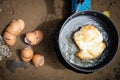 Top view,Fried egg in a pan of hot oil and eggshells on the sand near the pan,frying eggs for breakfast at the camping while