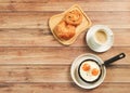 Top view of fried eggs in pan , cup of coffee and  danish pastry and Croissant on wooden background Royalty Free Stock Photo