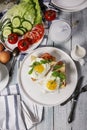 Top view fried eggs with spices, fresh basil and herbs on a white plate. Fresh cucumber and tomato salad. Morning food still life Royalty Free Stock Photo
