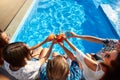 Top view of of friends clinking glasses with fresh colorful cocktails sitting by swimming pool on sunny summer day