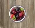 Top view. Fruits and berries in bowl on wooden background. Ripe currants, raspberries, cherries, strawberries, gooseberries, black Royalty Free Stock Photo