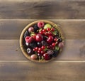 Top view. Fruits and berries in bowl on wooden background. Ripe currants, raspberries, cherries, strawberries, gooseberries, black Royalty Free Stock Photo