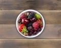 Top view. Fruits and berries in bowl on wooden background. Ripe currants, raspberries, cherries, strawberries, gooseberries, black Royalty Free Stock Photo