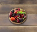 Top view. Fruits and berries in bowl on wooden background. Ripe currants, raspberries, cherries, strawberries, gooseberries, black Royalty Free Stock Photo