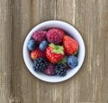 Top view. Fruits and berries in bowl on wooden background. Ripe raspberries, strawberries, blackberries and blueberries. Backgroun Royalty Free Stock Photo