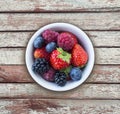 Top view. Fruits and berries in bowl on wooden background. Ripe raspberries, strawberries, blackberries and blueberries. Backgroun Royalty Free Stock Photo