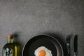 top view of frying pan with fried egg, cutlery and bottle of oil on grey Royalty Free Stock Photo