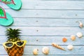 Top view funny Pineapple sea shell wore red sunglasses,sandal and hat on blue wooden background with copy space for summer holiday Royalty Free Stock Photo