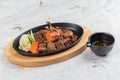 top view of Garlic Saikoro Steak: medium rare dice wagyu topping with mince carrot on hot plate served with potato salad. Royalty Free Stock Photo