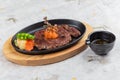 top view of Garlic Saikoro Steak: medium rare dice wagyu topping with mince carrot on hot plate served with potato salad. Royalty Free Stock Photo