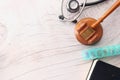 Top view of gavel, stethoscope and pills on wooden background